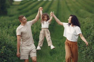 Joyful family moment in a green field during summer, capturing love and playfulness.